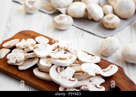 Gehackte Pilze auf Holz Schneidebrett, close-up. Weiß Holz- Hintergrund. Von der Seite. Stockfoto