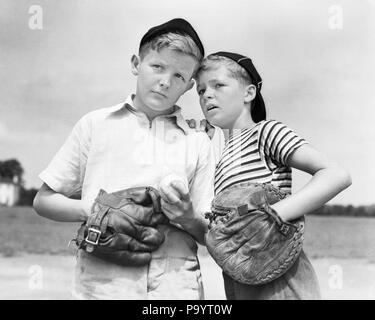 1930er Jahre zwei Jungen tragen Baseball Mützen und Handschuhe CATCHER UND KRUG PLANUNG STRATEGIE WHISPERING-b 1990 HAR 001 HARS GESUNDHEIT KOPIE RAUM MIT HALBER LÄNGE MÄNNCHEN PLANUNG GESCHWISTER AUSDRÜCKE B&W SOMMER ZIELE KRUG GLÜCK STRATEGIE CATCHER MITT UND ERHOLUNG FAUSTHANDSCHUHE GESCHWISTER VERBINDUNG KAPPEN BALL SPIEL BALL SPORT ZUSAMMENARBEIT JUGENDLICHE SCHWARZE UND WEISSE KAUKASISCHEN ETHNIE HAR 001 ALTMODISCH Stockfoto