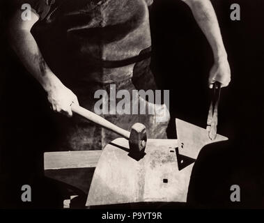 1935 s CLOSE-UP ANONYME SILHOUETTED SCHMIED HÄNDE ARBEITEN METALL auf den Amboss mit Hammer-i 3909 HAR 001 HARS HAR 001 ALTMODISCH Stockfoto