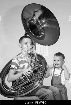 1950er Jahre jugendlich Junge IN STRIPE SHIRT JEANS SPIELEN TUBA kleiner Bruder im BIB OVERALLS LÄCHELND INDEX FINGER IN BEIDE OHREN-m11627 TAY001 HARS JEANS AUSDRUCK ALTE ZEIT NOSTALGIE BRUDER OLD FASHION 1 JUVENILE GESICHTSPFLEGE OHREN KOMMUNIKATION INSTRUMENTE COMIC SICHERHEIT FINGER LÄRM FAMILIEN LIFESTYLE HORN KLANG MUSIKER BROTHERS HOME LEBEN KOMMUNIKATION STREIFEN halber Länge PERSONEN OVERALLS MÄNNER GEFAHR JUGENDJUNGEN UNTERHALTUNG GESCHWISTER AUSDRÜCKE B&W HÖRNER MUSIKER ÜBERGROSSE PERFORMING ARTS INDEX SONDERBARE URLAUBS HANDBUCH SCHUTZ STECKEN LAUT OVERSIZE LEISTUNGSSTARKE ZANY UNKONVENTIONELLE GESCHWISTER LÄCHELN Stockfoto