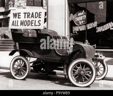 1930er Jahre antikes Auto mit WIR HANDEL ALLE MODELLE WERBESCHILD GEPARKT AUF STRASSE VOR AUTOHAUS-m 1583 HAR 001 HARS SCHWARZ UND WEISS HAR 001 ALTMODISCH Stockfoto