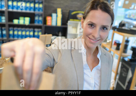 Shop Assistant, ein wenig Shopping Bag an den Kunden Stockfoto