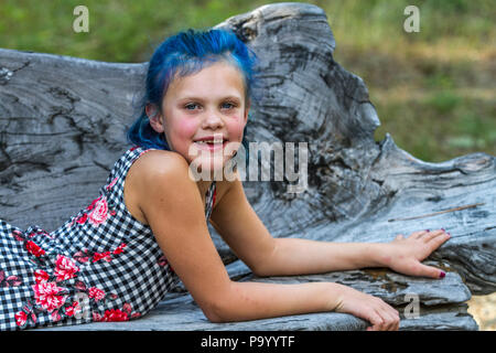 Atrtractive 8 jähriges Mädchen, in bunten jump Suit, die Haare hell blau gefärbt, an der Kamera auf der Suche und Festlegung auf der Werkbank. Model Release #113 Stockfoto