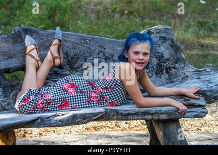 Atrtractive 8 jähriges Mädchen, in bunten jump Suit, die Haare hell blau gefärbt, an der Kamera auf der Suche und Festlegung auf der Werkbank. Model Release #113 Stockfoto