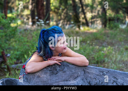 Atrtractive 8 jähriges Mädchen, in bunten jump Suit, Haare gefärbt ist hellblau, lehnte sich auf der Werkbank, Seite Profil. Model Release #113 Stockfoto