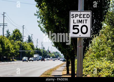 50 mph Höchstgeschwindigkeit Zeichen auf Post mit einer Straße und Baum mit Buchsen Stockfoto