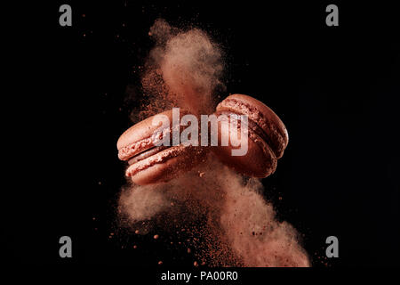 Französische Schokolade Macaron mit Kakaopulver auf schwarzem Hintergrund Stockfoto