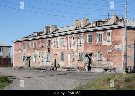 Die Einheimischen vor einem heruntergekommenen Gehäuse Block in Lorino, Tschukotka, Russland Stockfoto