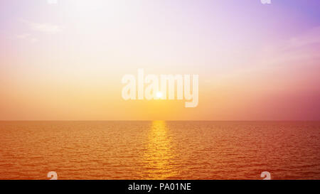 Die Sonne scheint golden in den Abend am Meer. Stockfoto