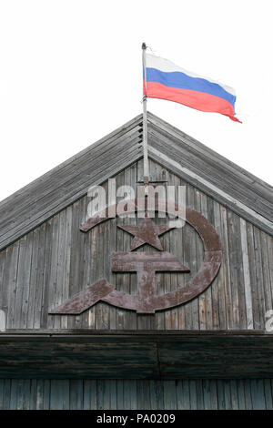 Russische Fahne über dem alten sowjetischen Hammer und Sichel in kleinen russischen Dorf in Kamtschatka Stockfoto