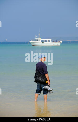 Man Paddeln im seichten Wasser am Strand von St Ives in Cornwall. Stockfoto