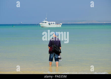 Man Paddeln im seichten Wasser am Strand von St Ives in Cornwall. Stockfoto