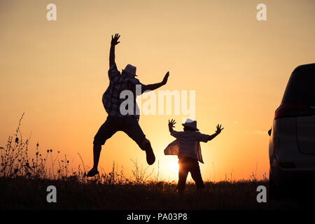 Vater und Sohn spielen in den Park am Sonnenuntergang. Menschen, die Spaß im Freien. Konzept der Sommerferien und freundliche Familie. Stockfoto