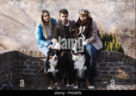 Mann mit zwei Frauen, die Freunde genießen Herbst Nachmittag mit seinen zwei Berner Sennenhunde Stockfoto