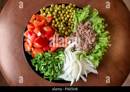 Abstrakte, verschwommen gedreht. Frisch zubereitete Gemüse Salate auf Platte auf rustikalen Hintergrund. Thunfisch mit grünen Salat, Erbsen, Paprika oder Paprika, Zwiebel Stockfoto