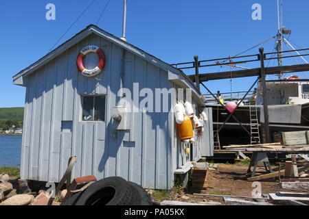 Die Werft in Annapolis Royal Wharf ist ein Bienenstock der Tätigkeit mit bunten Bojen Auflegen auf die hellgraue Schuppen und ein Boot überholt wird. Stockfoto