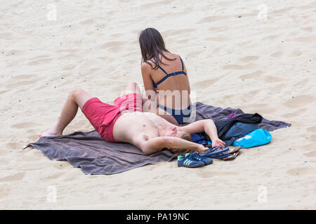 Bournemouth, Dorset, Großbritannien. Juli 2018 20. UK Wetter: heiß und feucht, mit trüben Sonnenschein in Bournemouth, als Sonnenanbeter Kopf ans Meer in Bournemouth Strand das schöne Wetter zu genießen. Junges Paar sonnenbaden. Credit: Carolyn Jenkins/Alamy leben Nachrichten Stockfoto