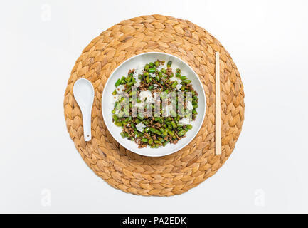 Schüssel mit Hackfleisch Eintopf mit Bohnen serviert über gekochten Reis mit Essstäbchen und Löffel auf eine Runde Strohmatte Stockfoto