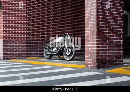 Handgefertigte Motorrad Parkplatz in der Nähe der Mauer der industriellen Gebäude. Alles ist bereit für Spaß nach einem harten Tag im Büro. Geschäftsmann Stadt hipst Stockfoto