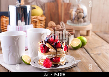 Sweet Home punkcakes mit weißer Sahne und frischen roten Beeren Himbeere. Zwei Gläser Tee zum Frühstück und einem Wasserkocher. Auf einem hölzernen Hintergrund. freier Platz für Text oder Werbung. Stockfoto