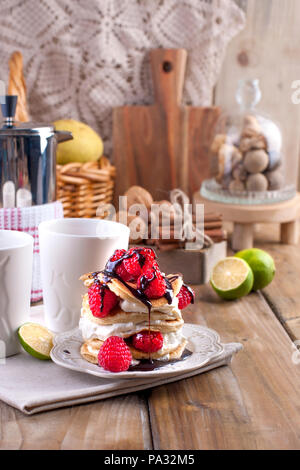 Sweet Home punkcakes mit weißer Sahne und frischen roten Beeren Himbeere. Zwei Gläser Tee zum Frühstück und einem Wasserkocher. Auf einem hölzernen Hintergrund. freier Platz für Text oder Werbung. Stockfoto