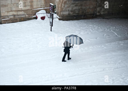 Auf einen erwachsenen Mann zu Fuß über Rahmen durch den Schnee unter Grau Sonnenschirm auf dem Weg zu einem Tunnel in Montpellier, Frankreich Stockfoto