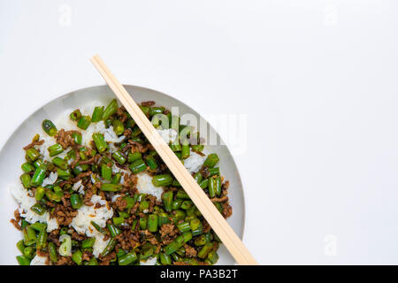 Schüssel mit Hackfleisch Eintopf mit Bohnen serviert über gekochten Reis mit Essstäbchen auf weißem Hintergrund Stockfoto