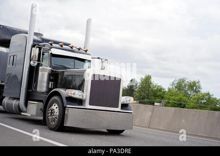 Schwarz klassische amerikanische Motorhaube leistungsstarke stilvolle Big Rig Semi Truck mit vertikalen Auspuffrohre und Chrom Akzent Teile auf der Kabine mit Schlafplatz für t Stockfoto