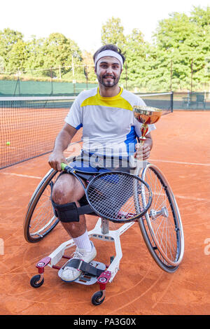 Junge Behinderte tennis player zeigt die Schale nach dem Gewinn der Outdoor Turnier Stockfoto