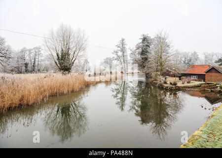 Ländlichen Surrey Winter Landschaft, Südost England, Fluss Wey in der Nähe von Pyrford bei niedrigen Temperaturen und Eisnebel, Spiegelungen der Bäume im Wasser Stockfoto