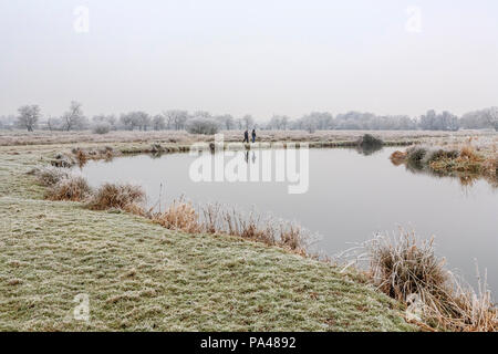 Ländlichen Surrey Landschaft, Südost England, zwei Menschen zu Fuß am Ufer des River Wey in der Nähe von Pyrford in sehr niedrigen Temperaturen im Winter Wetter Stockfoto