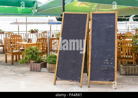 Zwei leere Tafel gegen Liegen und Schirme Stockfoto