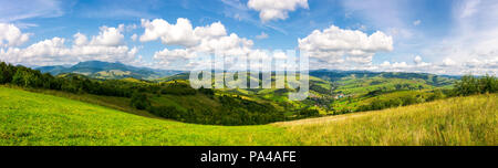 Panorama der gebirgigen Landschaft. schöne Landschaft Landschaft im frühen Herbst mit Wiese am Hang, Dorf, unten im Tal und Wolken o Stockfoto