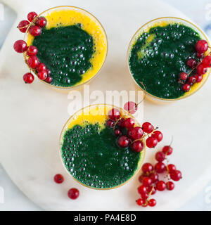 two colored fresh smoothies in glasses with fresh berries. orange banana juice with spirulina powder. detox breakfast. healthy eating Stockfoto