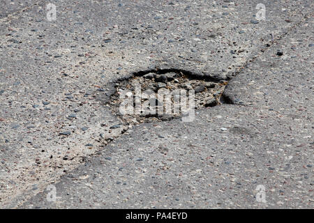 Ein großes Loch heraus geklopft in der Asphalt auf der Straße, eine Nahaufnahme der schlechten Infrastruktur, die Lage ist unverändert. Stockfoto