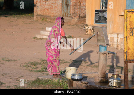 Indische Frau pumpen Wasser aus einem Brunnen im Dorf in Agra in der Nähe der Kanha Nationalpark, in Indien Stockfoto