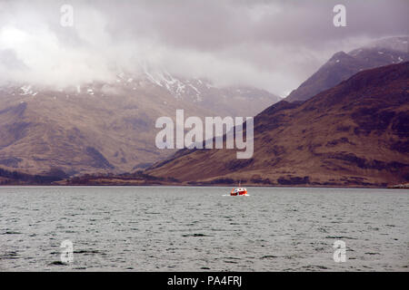 In den Bergen und Nebel über einem Boot im Loch Nevis vor der Küste der Halbinsel Knoydart, Northwest Highlands, Schottland, Großbritannien. Stockfoto