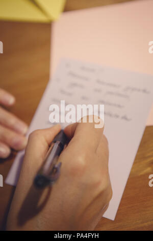 Nahaufnahme einer menschlichen Frau Hand mit Stift und schreiben Buchstaben oder Text auf Papier auf dem Hintergrund, selektiver Fokus, geringe Tiefenschärfe, getönt mit Stockfoto
