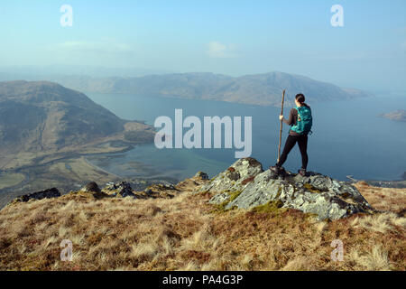 Eine weibliche Wanderer mit Stock auf einem Berg Aussichtspunkt auf sgurr Coire Choinnichean auf der Halbinsel Knoydart, Scottish Highlands, Schottland, Großbritannien. Stockfoto