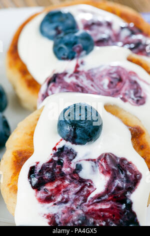 Ganze Beeren und Heidelbeeren Stau auf weiße Soße und schönen leckeren Käse Quark, close-up und Details von süßen Nachtisch Stockfoto