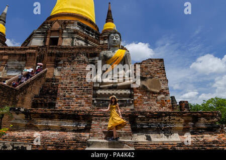 Porträt der schönen asiatischen Mädchen in langen Kleid posiert vor einem Big Buddha im Wat Yai Chai Mongkol. Die Wat ist in der Nähe von Ayutthaya. Stockfoto