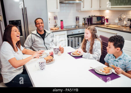 Familie von vier sind, genießen Sie das Frühstück gemeinsam zu Hause. Sie sind alle lachen, während sie Toast und Marmelade. Stockfoto