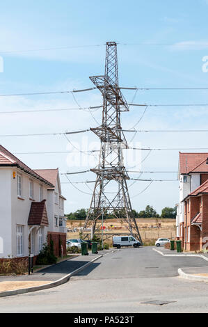 Eine Übertragung der Tower oder die auf dem Strom pylon trägt eine Oberleitung über ein Wohngebiet an der Ebbsfleet Garden City Entwicklung. Stockfoto