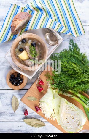 Traditionelle Suppe aus frischem Kohl und Zellstoff von Rindfleisch mit Kartoffeln, in eine hölzerne Schüssel auf einem weißen Hintergrund. In der Nähe befindet sich eine halb-ein-halb in verschiedenen Farben. Stockfoto