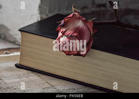 Rosa getrocknete Rose und altes Buch auf hölzernen Hintergrund Kopie Raum Stockfoto