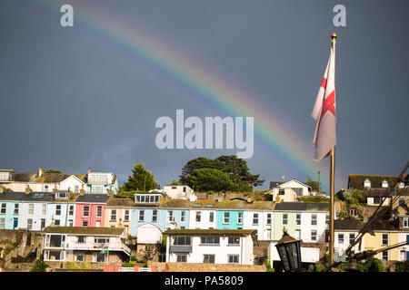 Bunte Häuser am Meer mit dunklem Himmel und Regenbogen, mit St. Georges Cross englische Flagge, Brixham, Devon Stockfoto