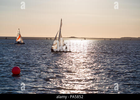 Segelboote auf dem See, West Kirby, Wirral, mit Sonnenlicht Wellen auf dem Wasser und Inseln im Hintergrund Stockfoto