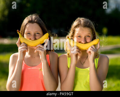 Zwei Mädchen teenager Freundin. Sommer in der Natur. In ihren Händen hält eine Banane. Das Konzept der Freude Spaß. Emotionen sind lustige Witze. Stockfoto