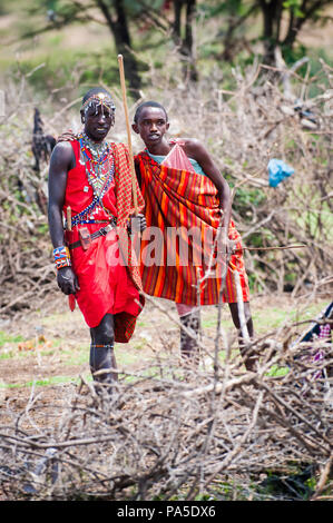 AMBOSELI, Kenia - 10. OKTOBER 2009: Unbekannter Massai Mann und Frau winken und Lächeln für die Kamera in Kenia, Oct 10, 2009. Massai Leute sind ein Stockfoto