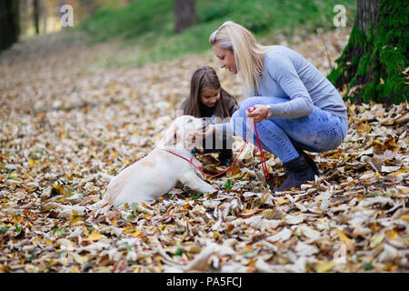 Mutter und Tochter mit ihrem Labrador Retriever Welpen in Park. Stockfoto